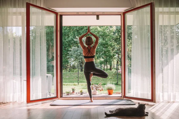 Žena Stojící Stromě Před Otevřeným Oknem Zatímco Doma Cvičí Jógu — Stock fotografie