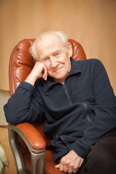 Portrait of a smiling old man in a chair — Stock Photo, Image