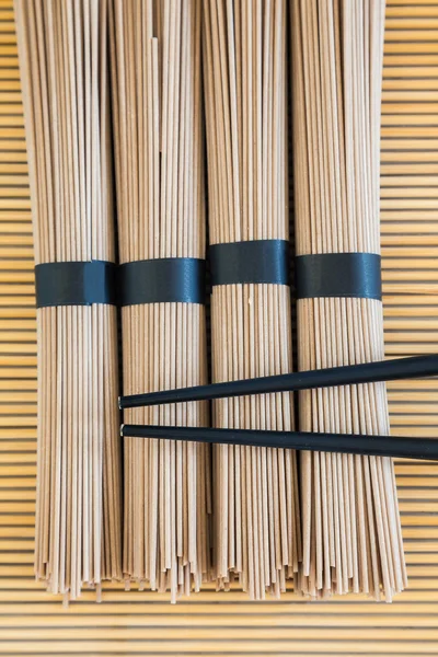 Soba macarrão e pauzinhos no fundo de bambu — Fotografia de Stock