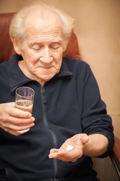 Old man holding a glass of water and pills — Stock Photo, Image