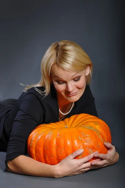 Pretty blonde woman in a costume of witch posing with pumpkins — Stock Photo, Image