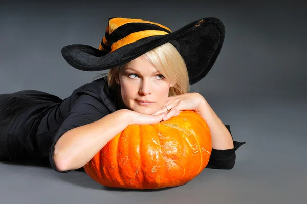Pretty blonde woman in a costume of witch posing with pumpkins — Stock Photo, Image