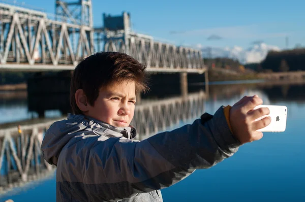 Мальчик перед железнодорожным мостом делает селфи — стоковое фото