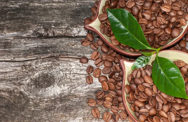 Granos de café y hojas sobre fondo de madera — Foto de Stock