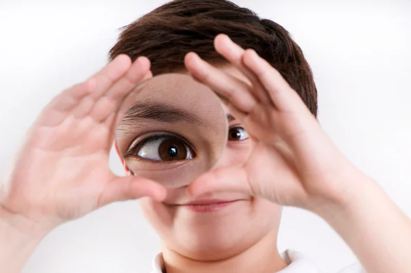 Boy looks at through a magnifying glass — Stock Photo, Image