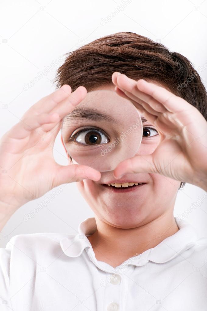 Boy looks at through a magnifying glass