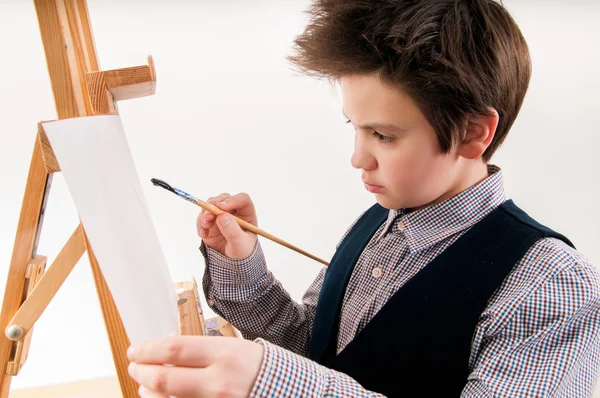 Kunstenaar school jongen schilderij borstel aquarellen portret op een ezel — Stockfoto