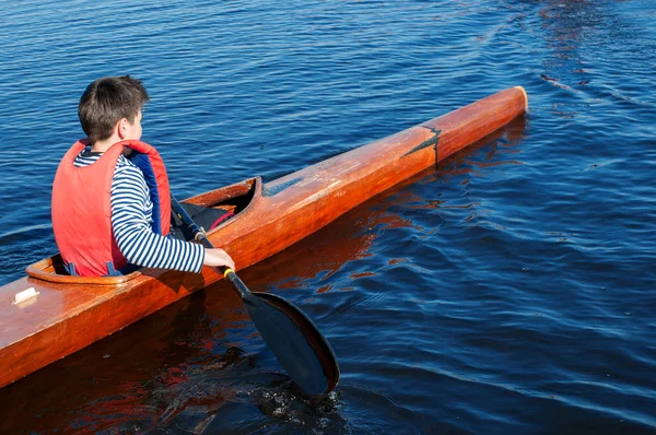 Pojken rodd i en kajak på floden — Stockfoto