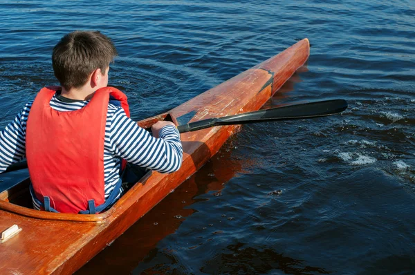 Pojken rodd i en kajak på floden — Stockfoto