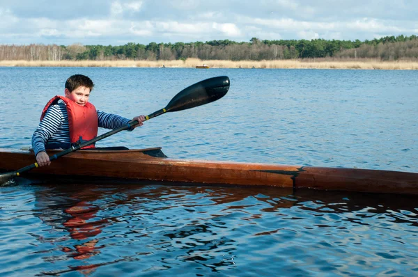 Le garçon ramant dans un kayak sur la rivière — Photo