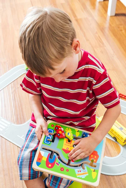 little boy plays board game with cars