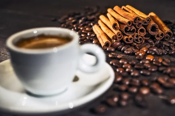 Cup of coffee with cinnamon and beans. Focus on cinnamon — Stock Photo, Image