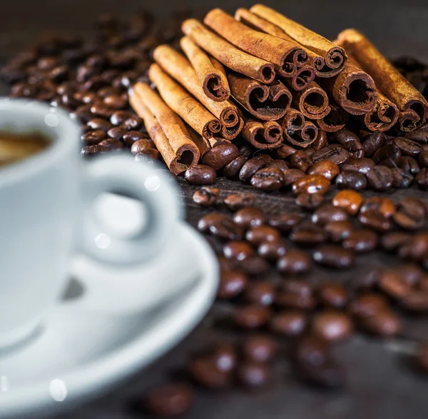 Cup of coffee with cinnamon and beans. Focus on cinnamon — Stock Photo, Image