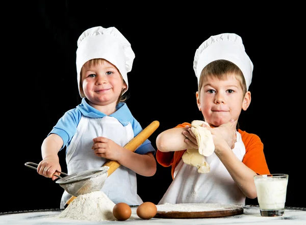 İki küçük çocuk yapma pizza veya makarna hamur. Siyah izole. — Stok fotoğraf