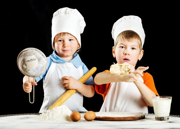 Dua anak kecil membuat pizza atau adonan pasta. Terisolasi di atas hitam — Stok Foto