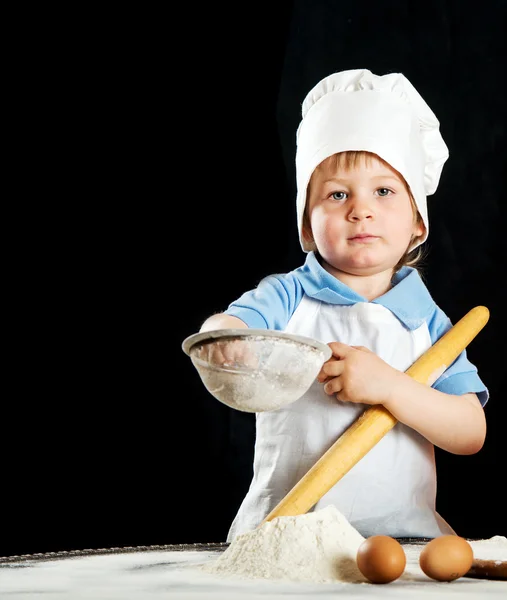 Kleiner Junge bei der Herstellung von Pizza oder Nudelteig. isoliert auf schwarz. — Stockfoto