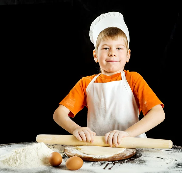 Kleiner Junge bei der Herstellung von Pizza oder Nudelteig. isoliert auf schwarz. — Stockfoto