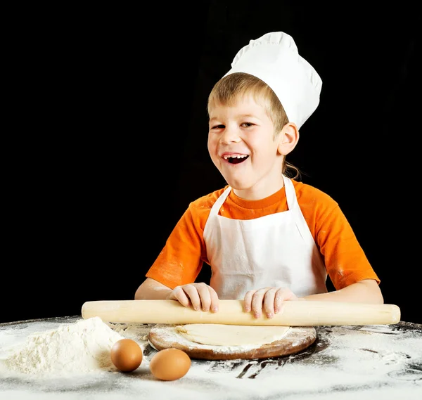 Kleiner Junge bei der Herstellung von Pizza oder Nudelteig. isoliert auf schwarz. — Stockfoto