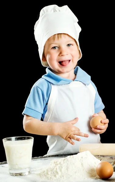 Kleiner Junge bei der Herstellung von Pizza oder Nudelteig. isoliert auf schwarz. — Stockfoto