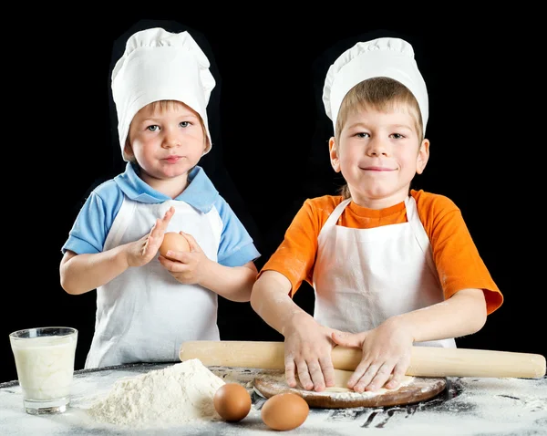 Two a little boy making pizza or pasta dough. Isolated on black — Stock Photo, Image