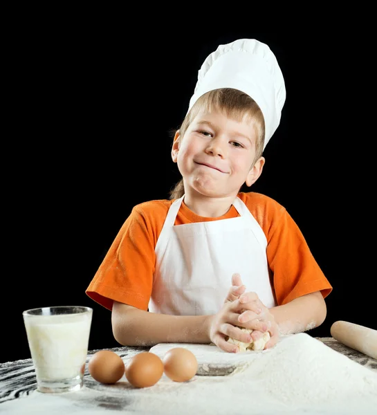 Kleiner Junge bei der Herstellung von Pizza oder Nudelteig. isoliert auf schwarz. — Stockfoto