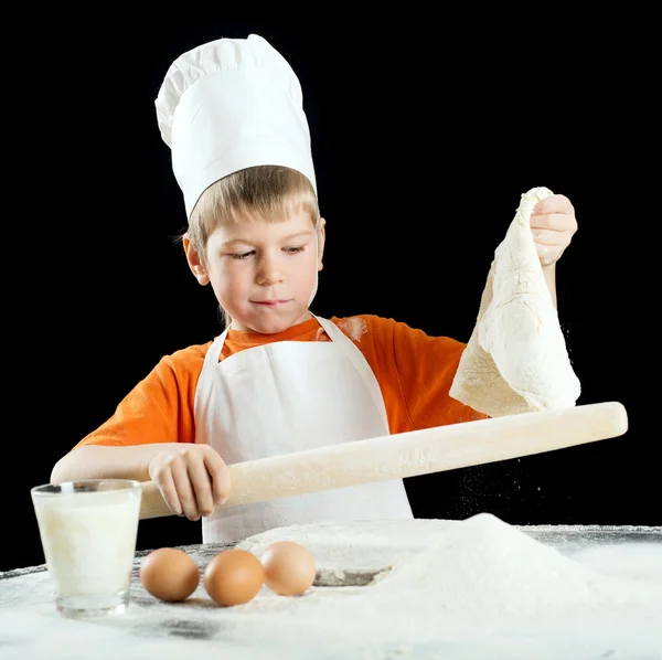 Little boy making pizza or pasta dough. Isolated on black. — Stock Photo, Image