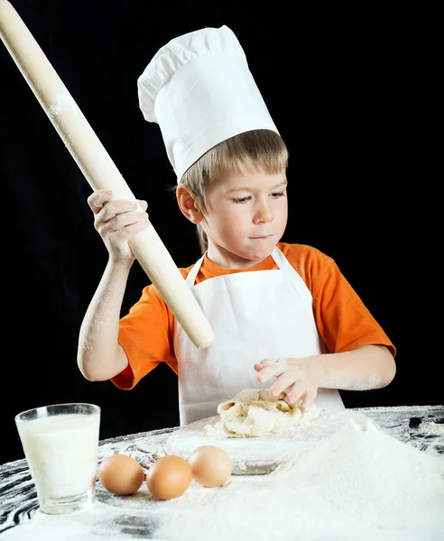 Мальчик делает пиццу или тесто для макарон. Изолированный на черном . — стоковое фото