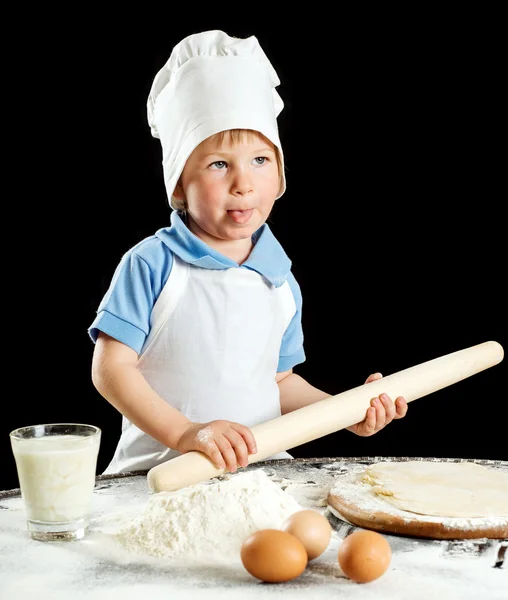 Kleiner Junge bei der Herstellung von Pizza oder Nudelteig. isoliert auf schwarz — Stockfoto