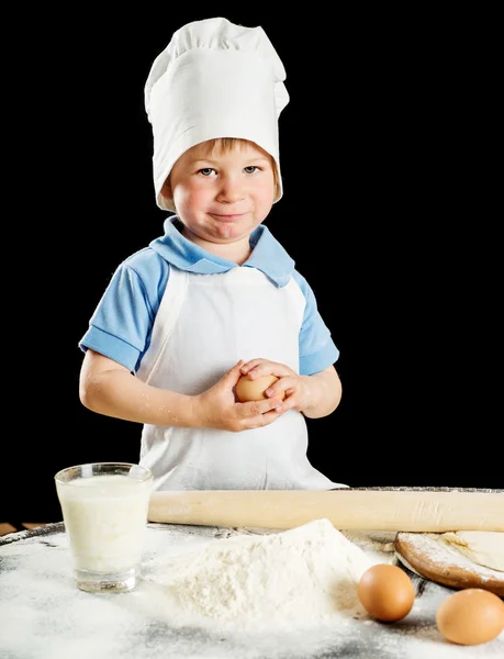 Kleiner Junge bei der Herstellung von Pizza oder Nudelteig. isoliert auf schwarz — Stockfoto