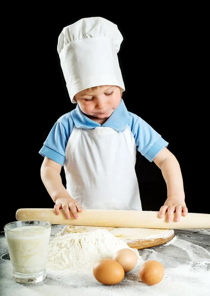 Little boy making pizza or pasta dough. Isolated on black — Stock Photo, Image