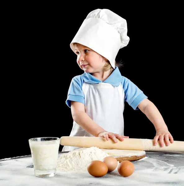 Маленький хлопчик робить піцу або тісто для макаронів. Ізольовані на чорному — стокове фото