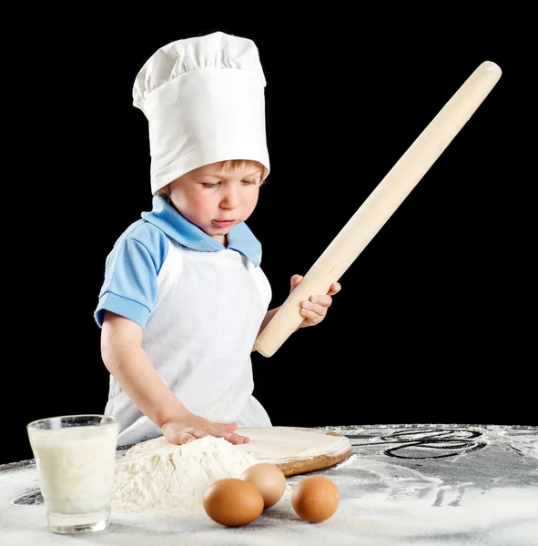 Мальчик делает пиццу или тесто для макарон. Изолированный на черном — стоковое фото