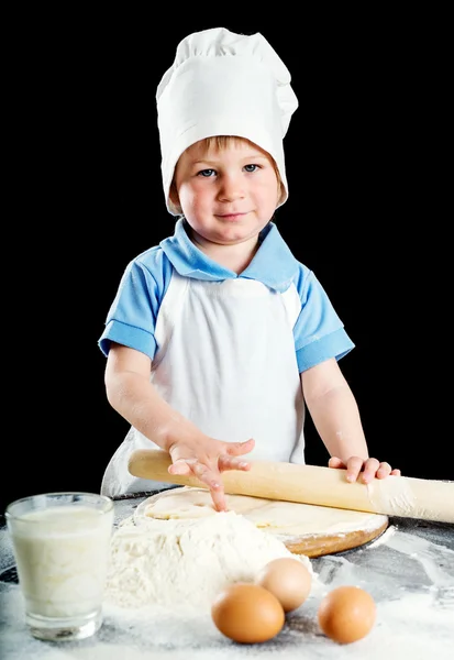 Kleiner Junge bei der Herstellung von Pizza oder Nudelteig. isoliert auf schwarz. — Stockfoto