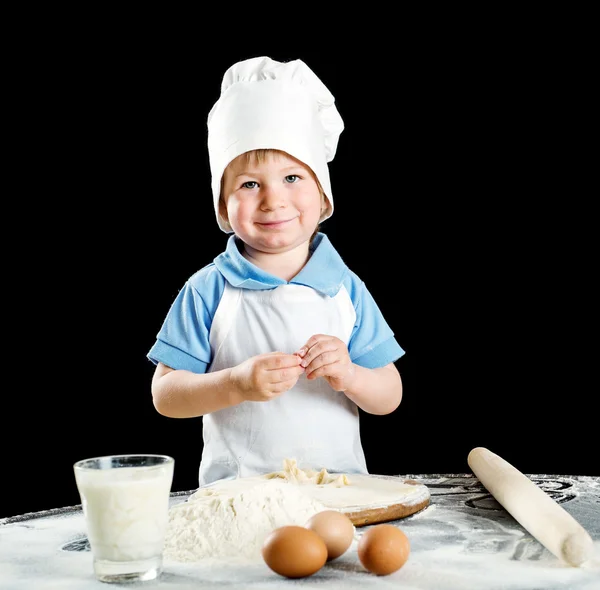 Kleiner Junge bei der Herstellung von Pizza oder Nudelteig. isoliert auf schwarz. — Stockfoto