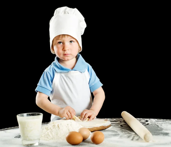 Маленький хлопчик робить піцу або тісто для макаронів. Ізольовані на чорному . — стокове фото