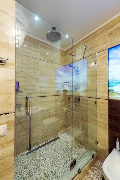 Lyse og hvide badeværelse med hvidt badekar, beige flisegulv, glasdør bruser - Stock-foto