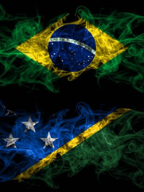 Brezilya, Brezilya Solomon Adaları 'na karşı yan yana yerleştirilmiş dumanlı mistik bayraklar. Kalın renkli ipeksi soyut duman bayrakları.