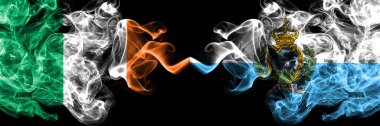 Republic of Ireland, Irish vs San Marino smoky mystic flags placed side by side. Thick colored silky abstract smoke flags.