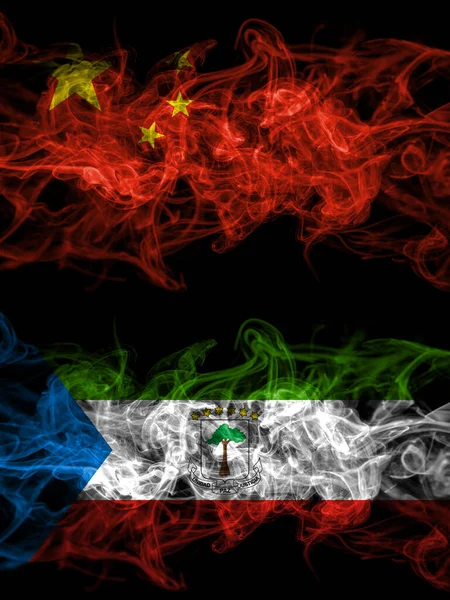 China, Chinese vs Equatorial Guinea smoky mystic flags placed side by side. Thick colored silky abstract smoke flags.