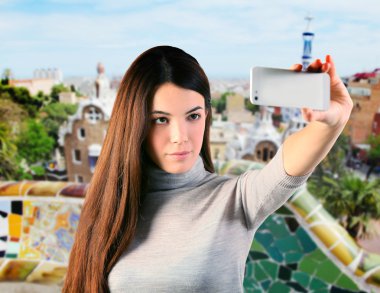Genç kadın söz Park Guell, Barselona, İspanya, smartphone ile kendi portresi.