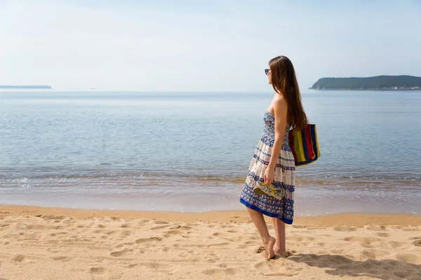 Jong meisje permanent aan het zandstrand — Stockfoto