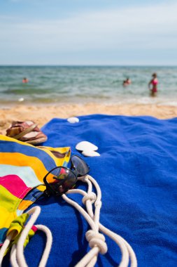 Plaj çantası, havlu ve gözlük kıyısında