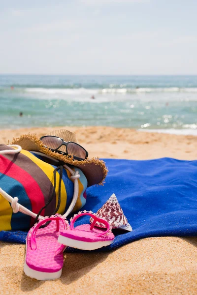 Hut, Sonnenbrille, Handtuch und andere Utensilien am Sandstrand — Stockfoto