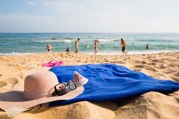 Chapéu, toalha, óculos de sol e chinelos em uma praia tropical — Fotografia de Stock