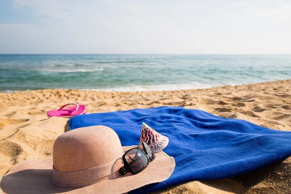 Hatt, handduk, solglasögon och tofflor på en tropisk strand — Stockfoto