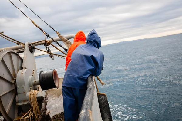 Рыбаки в водонепроницаемых костюмах на палубе рыболовного судна — стоковое фото