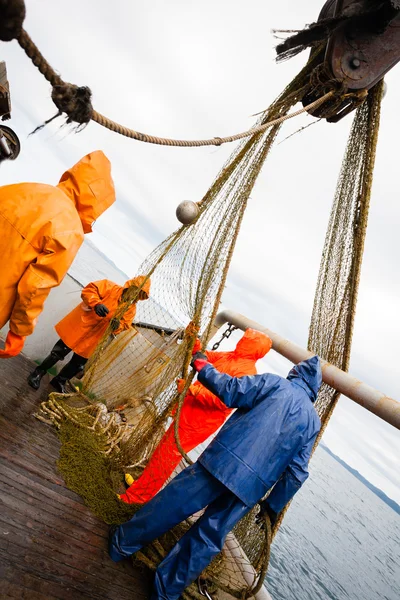 Vissers in waterdichte pakken op het dek van het vissersvaartuig — Stockfoto