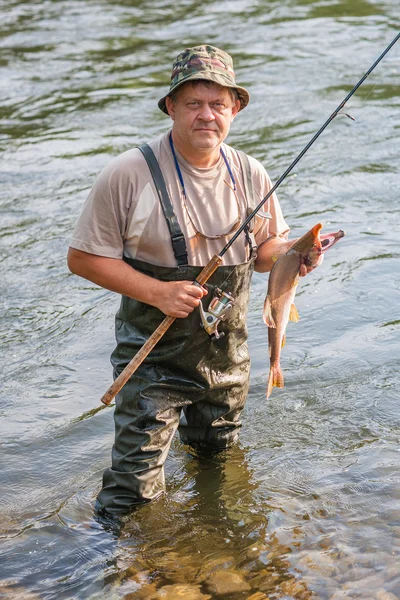 Pescador mantém salmão capturado — Fotografia de Stock