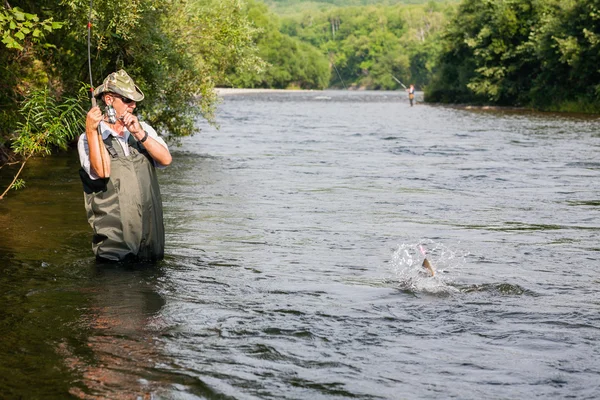 Радостный рыбак ловит лосося на горной реке — стоковое фото