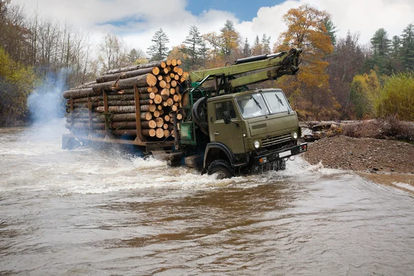 Heavy truck for transportation of logs moves ford in the river — Stock Image Heavy truck for transportation of logs moves ford in the river Stock Image